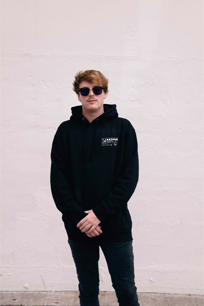 Daniel Mac in black hoodie standing against white wall