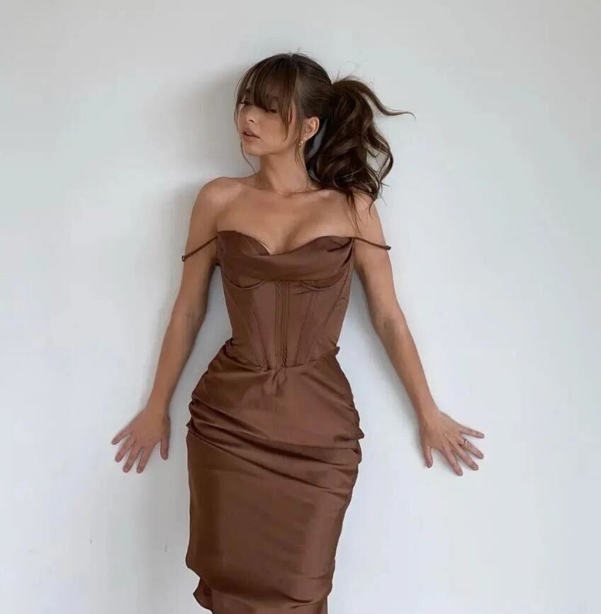 Riley Reid wearing brown strapless dress, standing against white wall